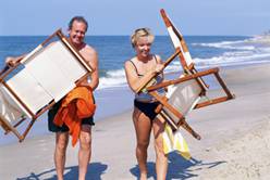 couple carrying beach chairs on beach